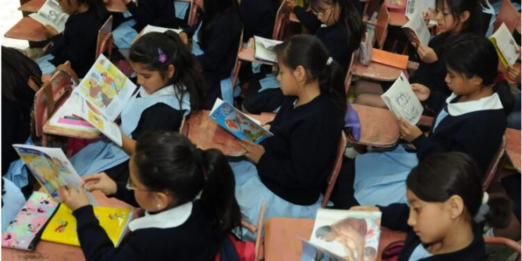 Alumnas leen libros con ilustraciones en el aula. Foto: Agencia Guatemalteca de Noticias (AGN).